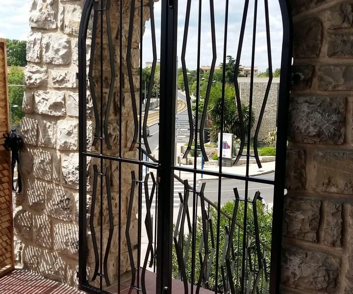 Porte double grille en arche vue terrasse Métal'Rine